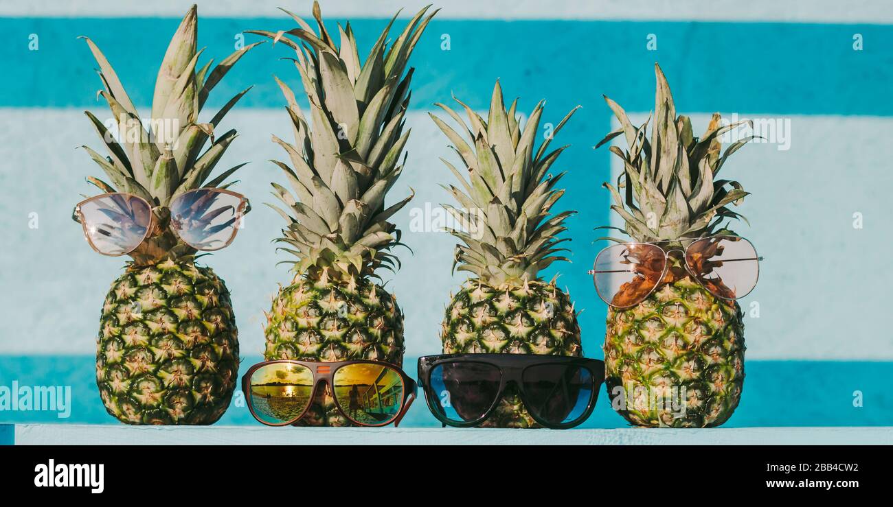 Nahaufnahme von lustigen frischen exotischen Früchten Ananas auf dem Tisch vor hellblauem Holzhintergrund. Modische Gruppe reifer Ananashipper-Familie im Styl Stockfoto