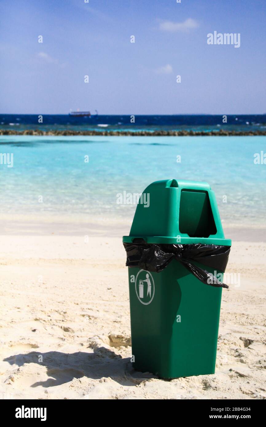 Grüner Kunststoffbehälter am sauberen tropischen Strand nach dem Recycling Stockfoto