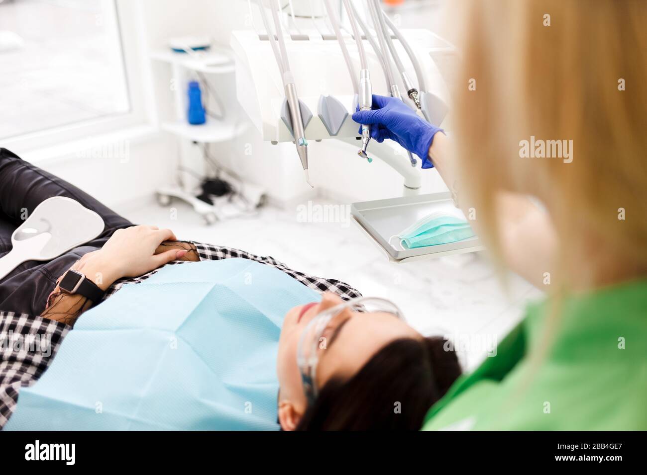 Zahnarzt nimmt einen Bohrer in der Hand, um die zahnärztliche Behandlung für ein junges Mädchen
