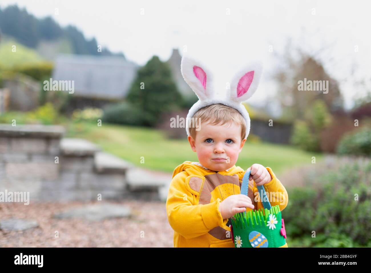 Junge draußen im Garten mit Hünenohren für die Ostereierjagd, Schottland, Großbritannien Stockfoto