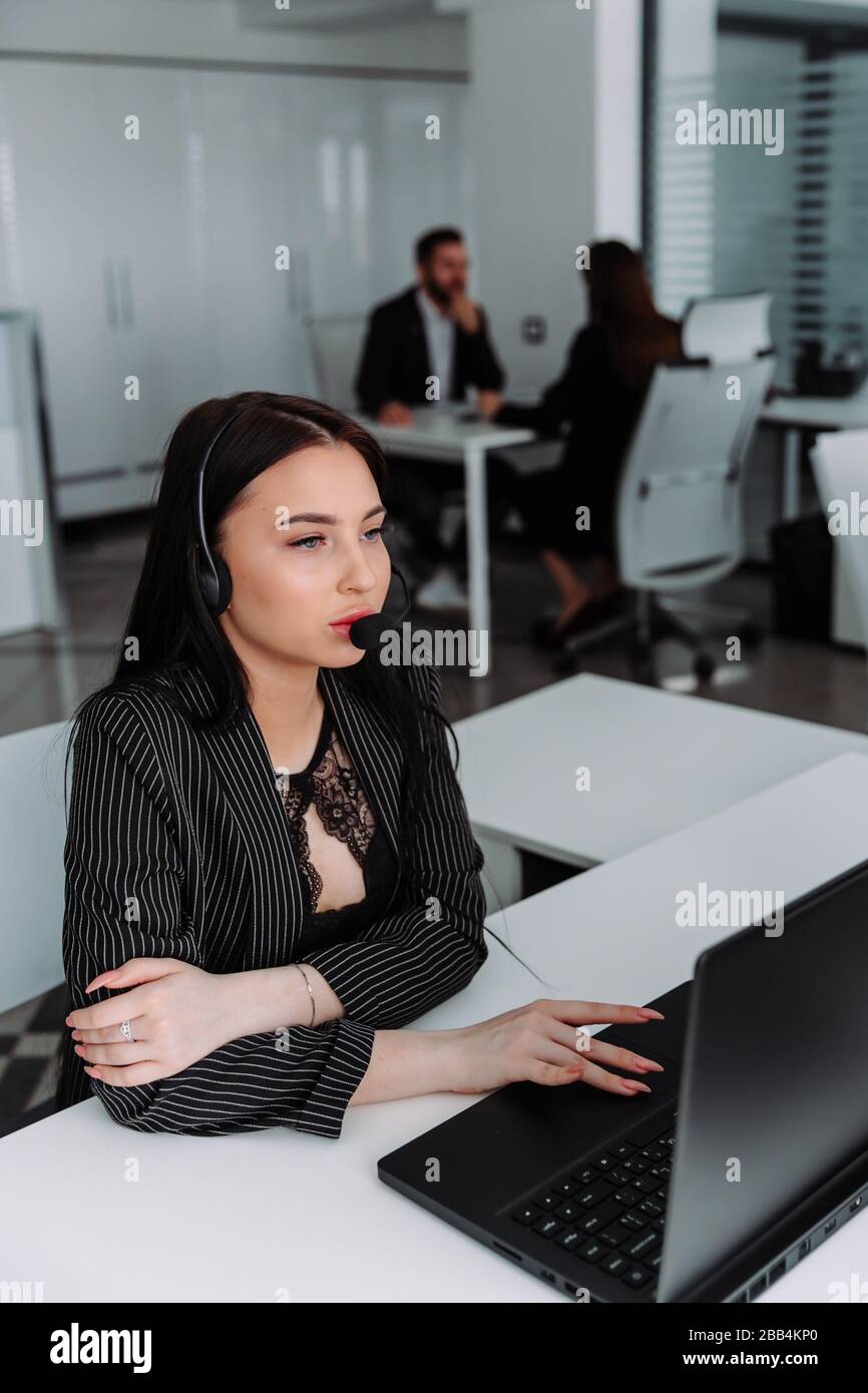 Ein junger Mitarbeiter, der mit einem Headset und einem Begleitteam arbeitet Stockfoto