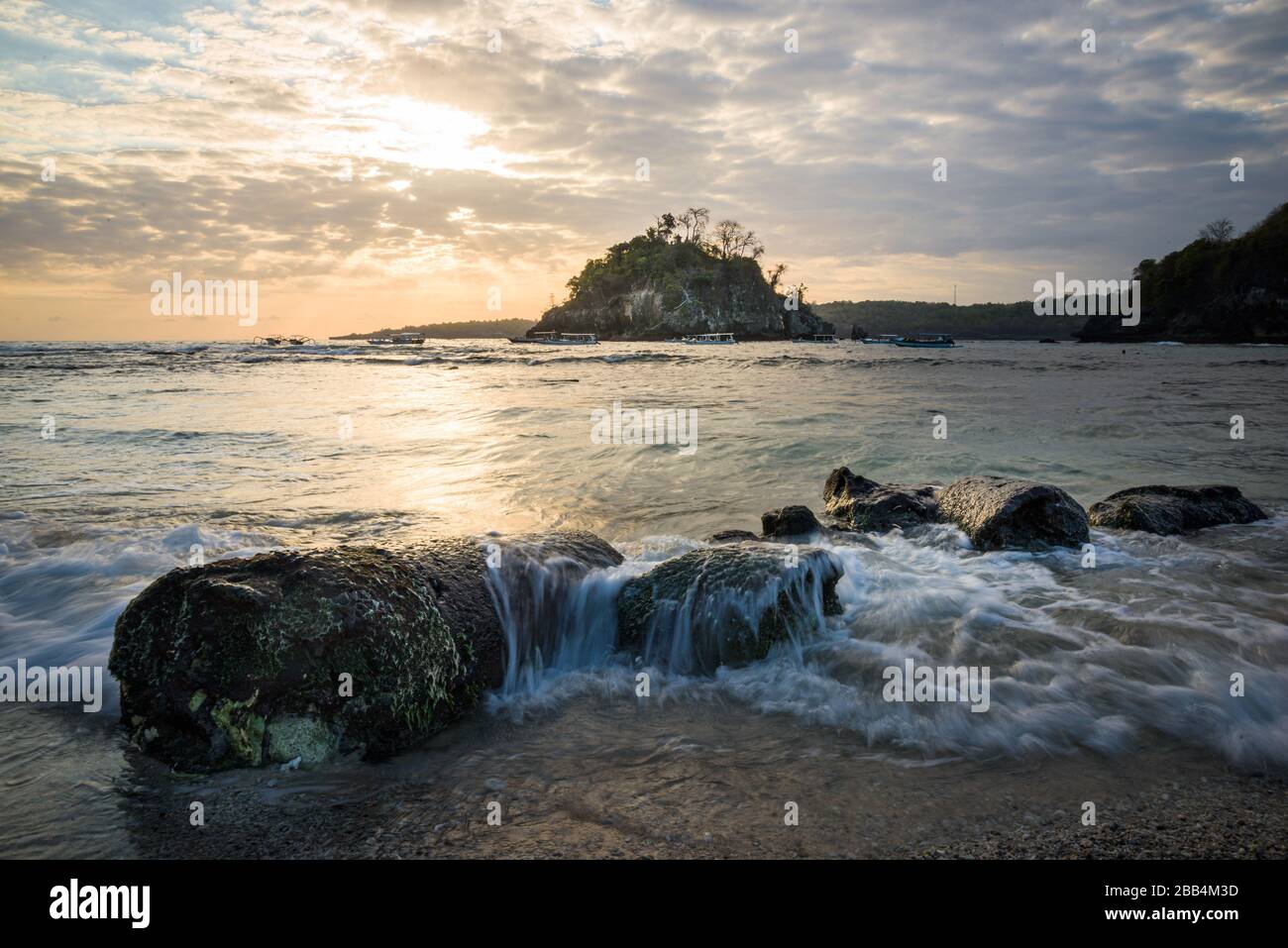 Crystal Bay bei Ebbe mit dem Sonnenuntergang durch die Felsinsel strömende Meerwasser über Felsen und Pfütze in Nusa Penida, Bali, Indonesien Stockfoto