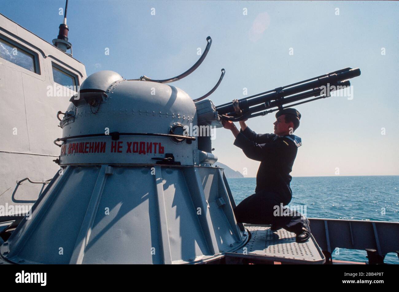 Ein junger KGB-Marine-Rating reinigt das Revolvergewehr auf einem Grenzschiff Schwarzes Meer, Krim, UdSSR, August 1990 Stockfoto