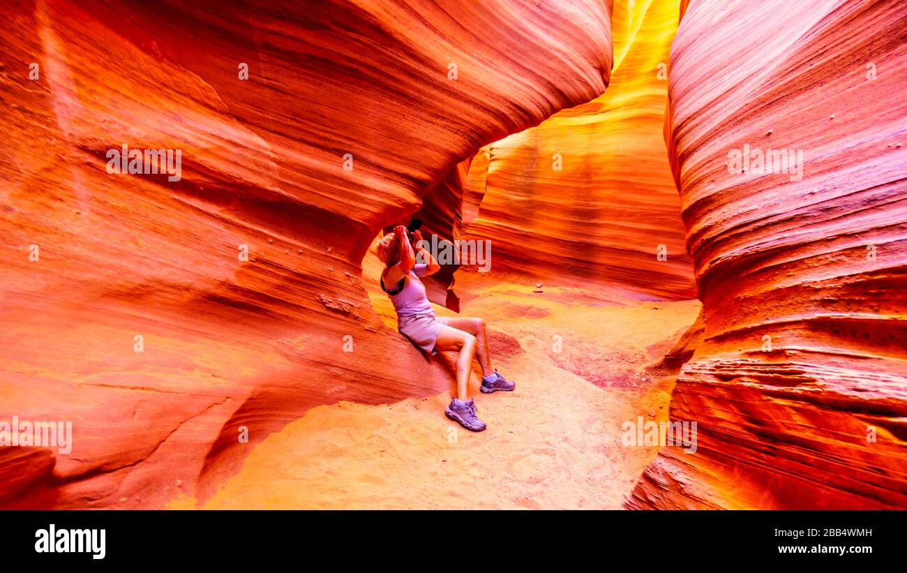 Frau, die ein Foto von den glatten geschwungenen Wänden aus rotem Navajo-Sandstein des Rattlesnake Canyon, einer der berühmten Schlitzkanonen in der Nähe von Page Arizona, machte Stockfoto