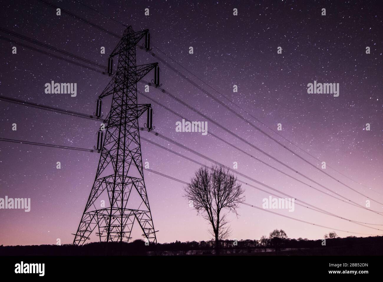 Sterne am Nachthimmel hinter dem Elektrizitätspylon in Sussex, Großbritannien, März Stockfoto