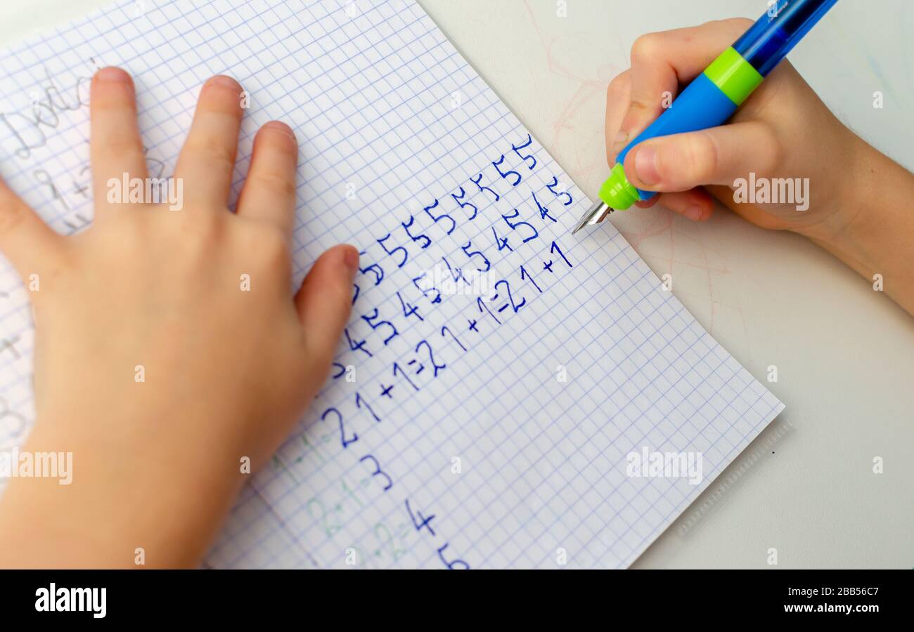 Kinder machen mathematische Hausaufgaben. Nahaufnahme der Hand des jungen Jungen mit Stift und Schreiben einer mathematischen Hausaufgabe Nahaufnahme. Konzept der Ausbildung am Hom Stockfoto