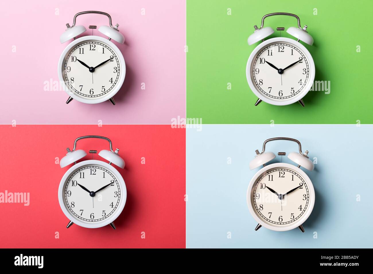 Weißer Vintage-Wecker auf blauem, pinkfarbenem, rotem und grünem Hintergrund. Zeitkonzept Stockfoto Weißer Vintage-Wecker auf blauem, pinkfarbenem, rotem und grünem Hintergrund. Zeitkonzept Stockfoto