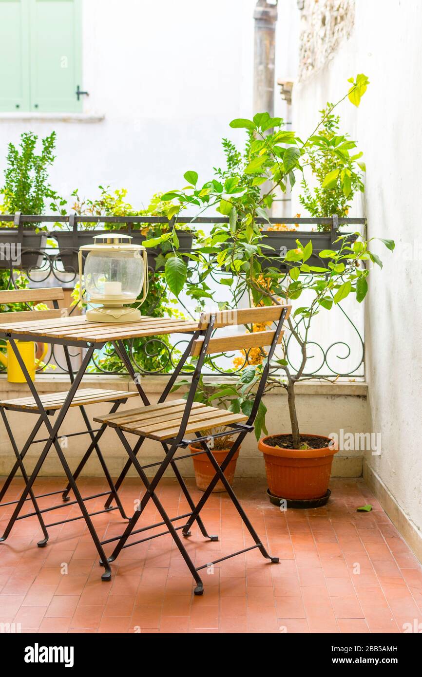 Ein italienischer Balkon mit grünen Topfpflanzen und Gartenmöbeln, ein Tisch und Stühle zum genießen des Balsagenabends. Stockfoto