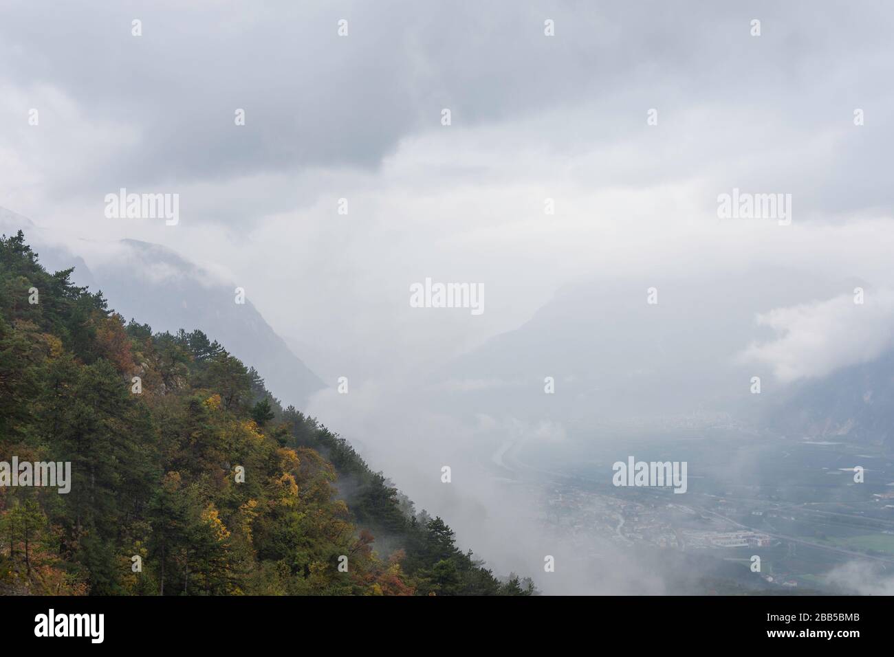 Sonnigen Herbstnachmittag Bergwelt. Bäume in Herbstfarben am Hang. grünes gras wiese. ridge in der Ferne. helles Wetter mit Wolken Stockfoto