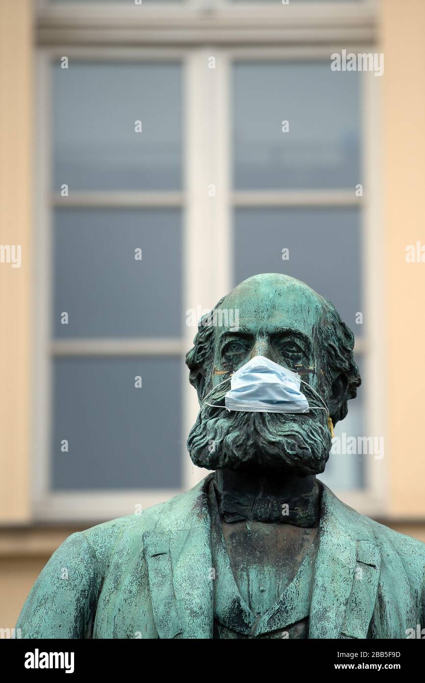 Bonn, Deutschland. März 2020. Jesters hat dem vom Bildhauer Hans Everding geschaffenen Chemikern und Naturwissenschaftler Friedrich August Kekulé ein Mundschutzgitter auf das Denkmal gesetzt. Das öffentliche Leben leidet derzeit unter den Maßnahmen zur Eindämmung der Corona-Pandemie. Kredit: Federico Gambarini / dpa / Alamy Live News Stockfoto