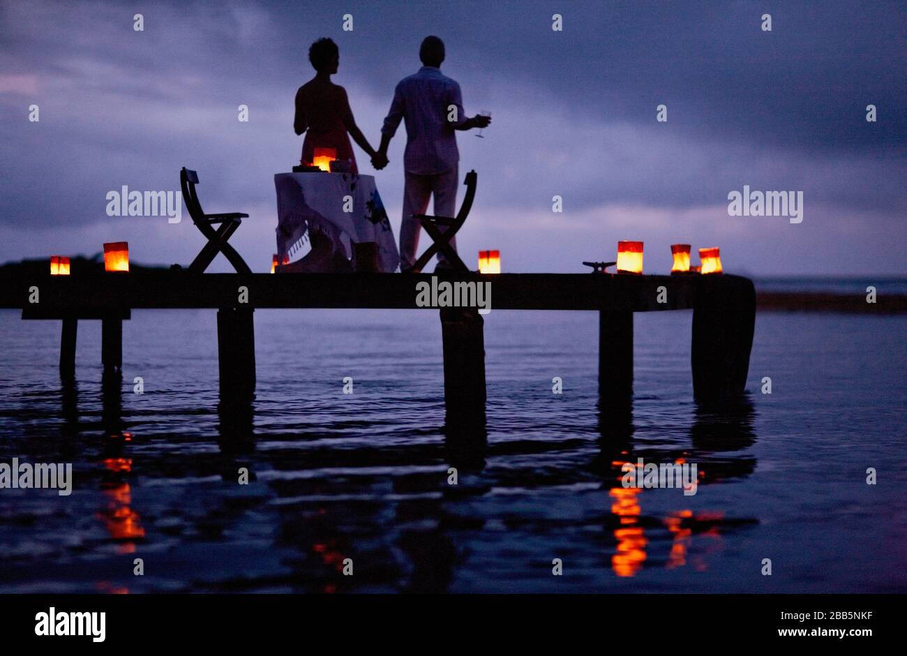 Reifere Paare genießen ihr Date am Pier in der Dämmerung. Stockfoto