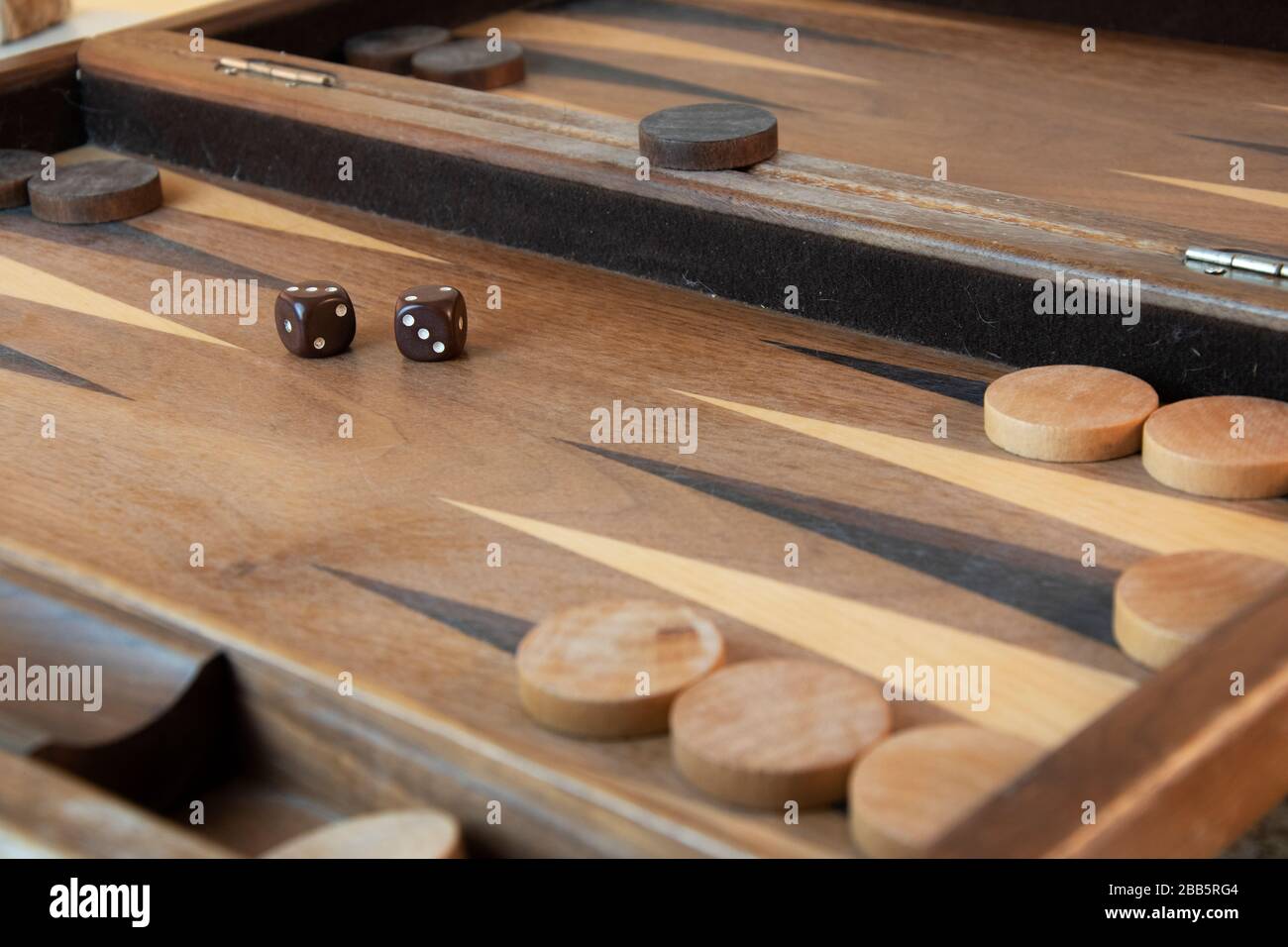 Braune Backgammon-Würfel und -Stücke auf Holzbrett Stockfoto