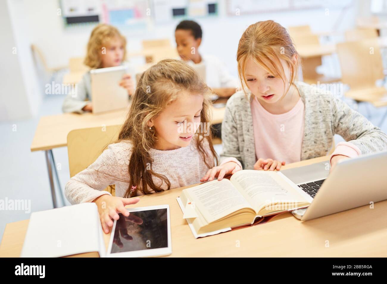 Mädchen Klasse einer Grundschule lernen in der Klasse auf einem Laptop Stockfoto