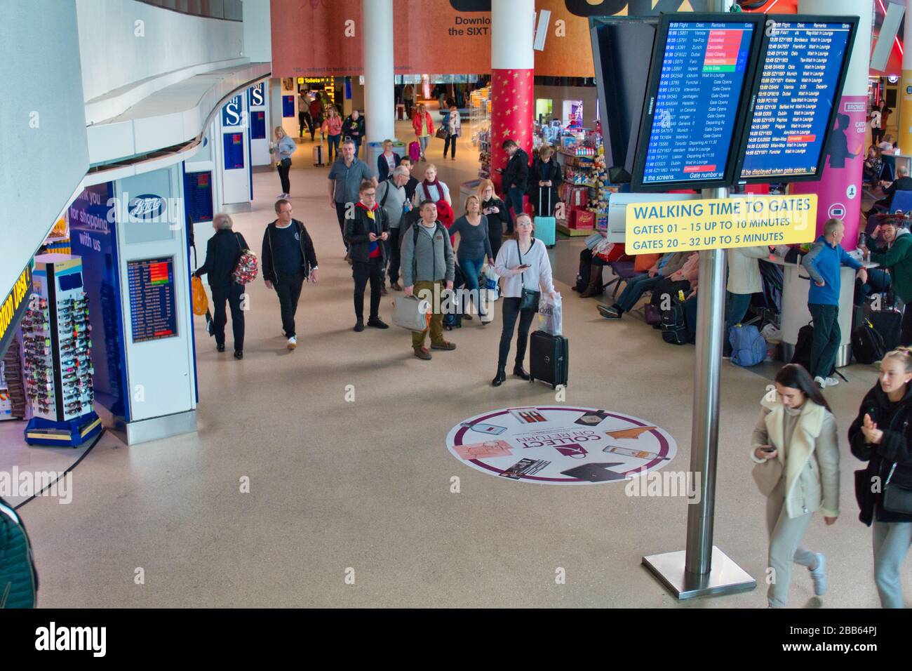 Flugreisende sehen die Abfluginformationen auf großen Videobildschirmen in einer Lounge am Ringway Airport von Manchester. Stockfoto