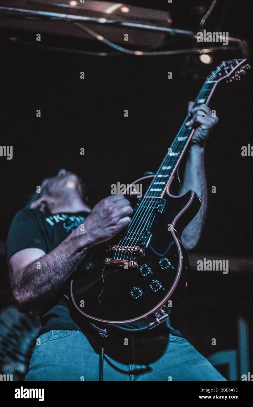 Ein Mann, der auf der Bühne Gitarre spielt. Dunkler Hintergrund, Strahler. Stockfoto