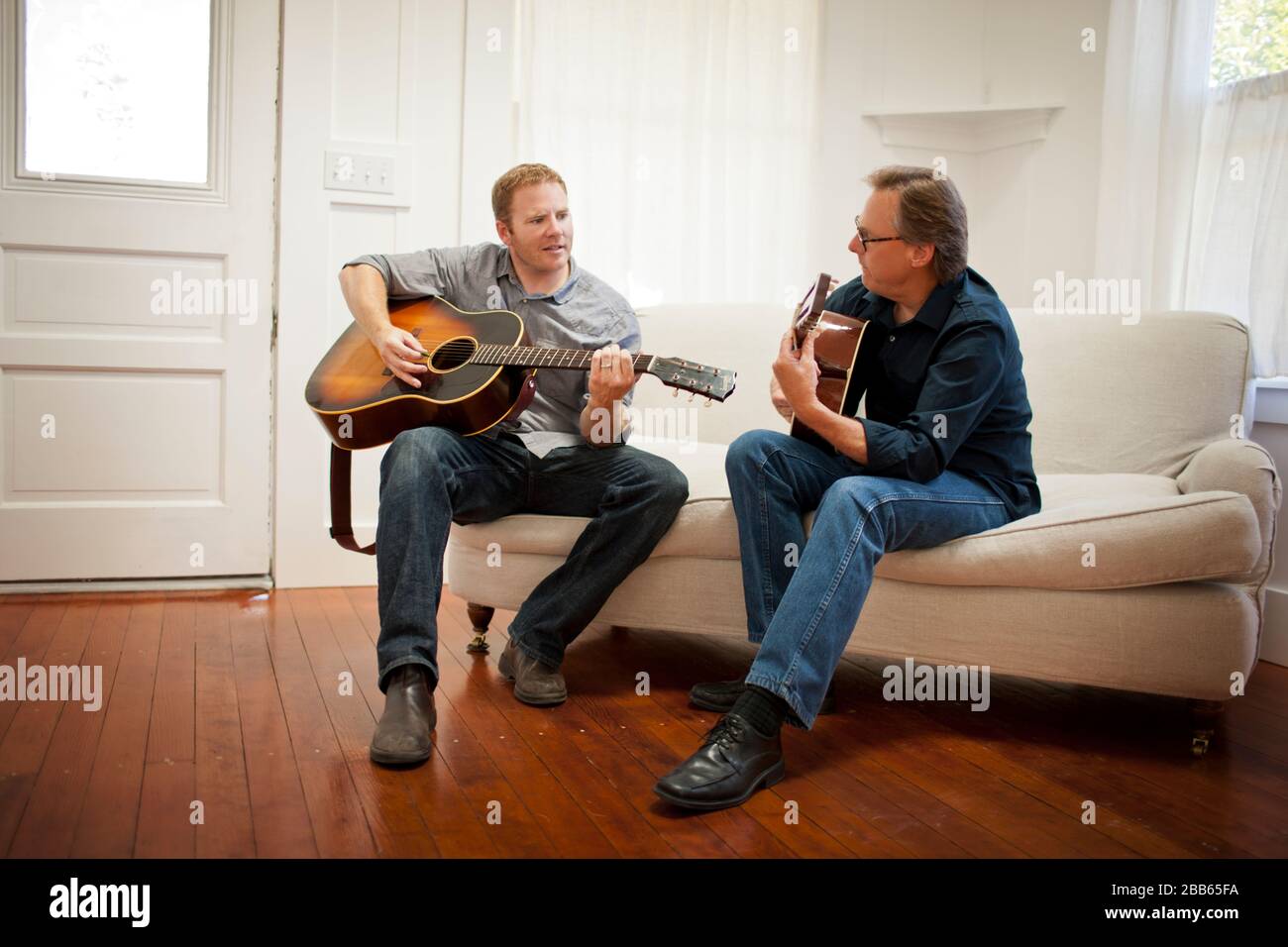 Mittlerer Erwachsener und reifer Mann, der akustische Gitarren spielt. Stockfoto