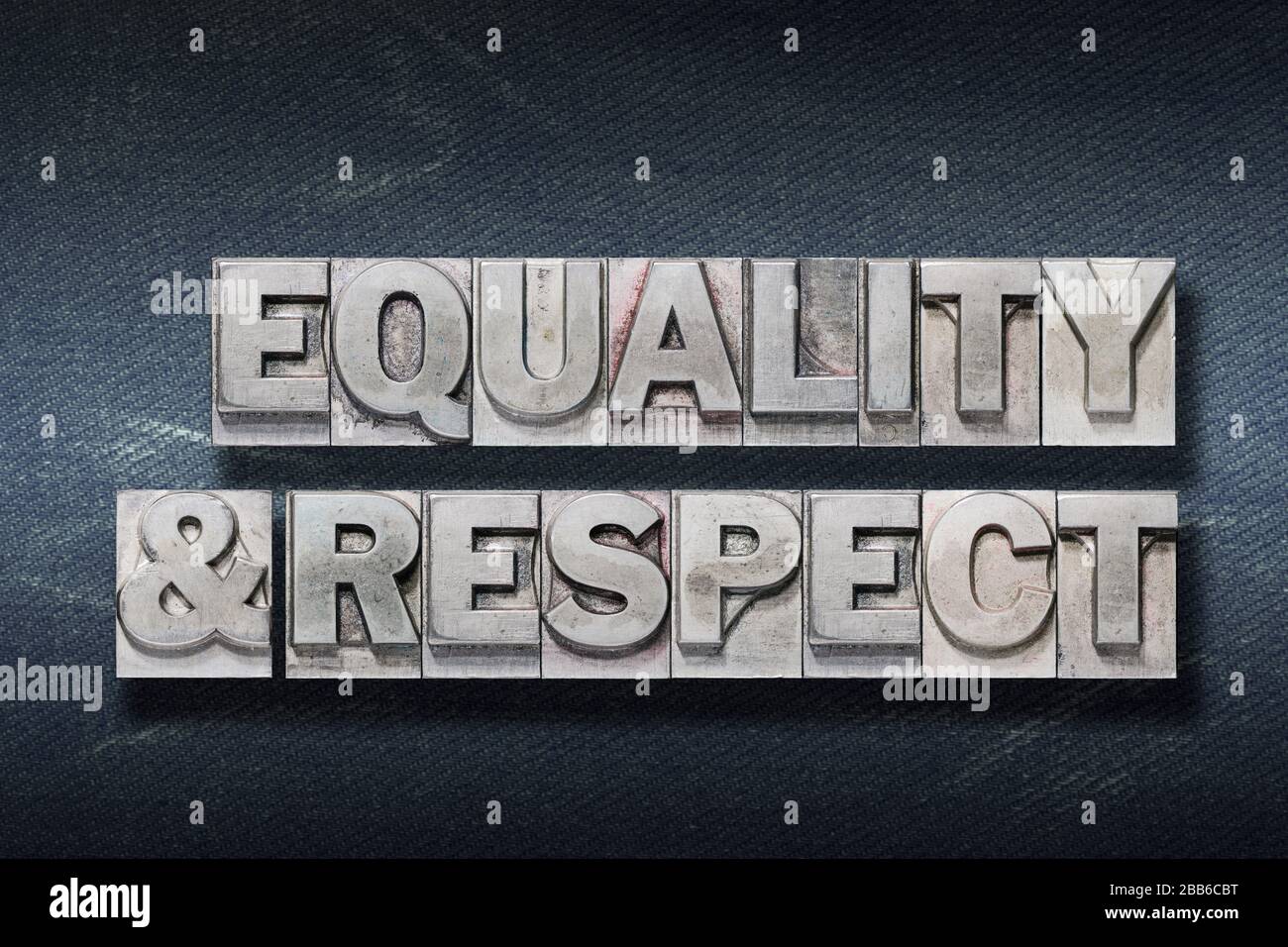 Gleichheits- und Respektworte aus metallischen Briefdrücken auf dunklem Jeanshintergrund Stockfoto