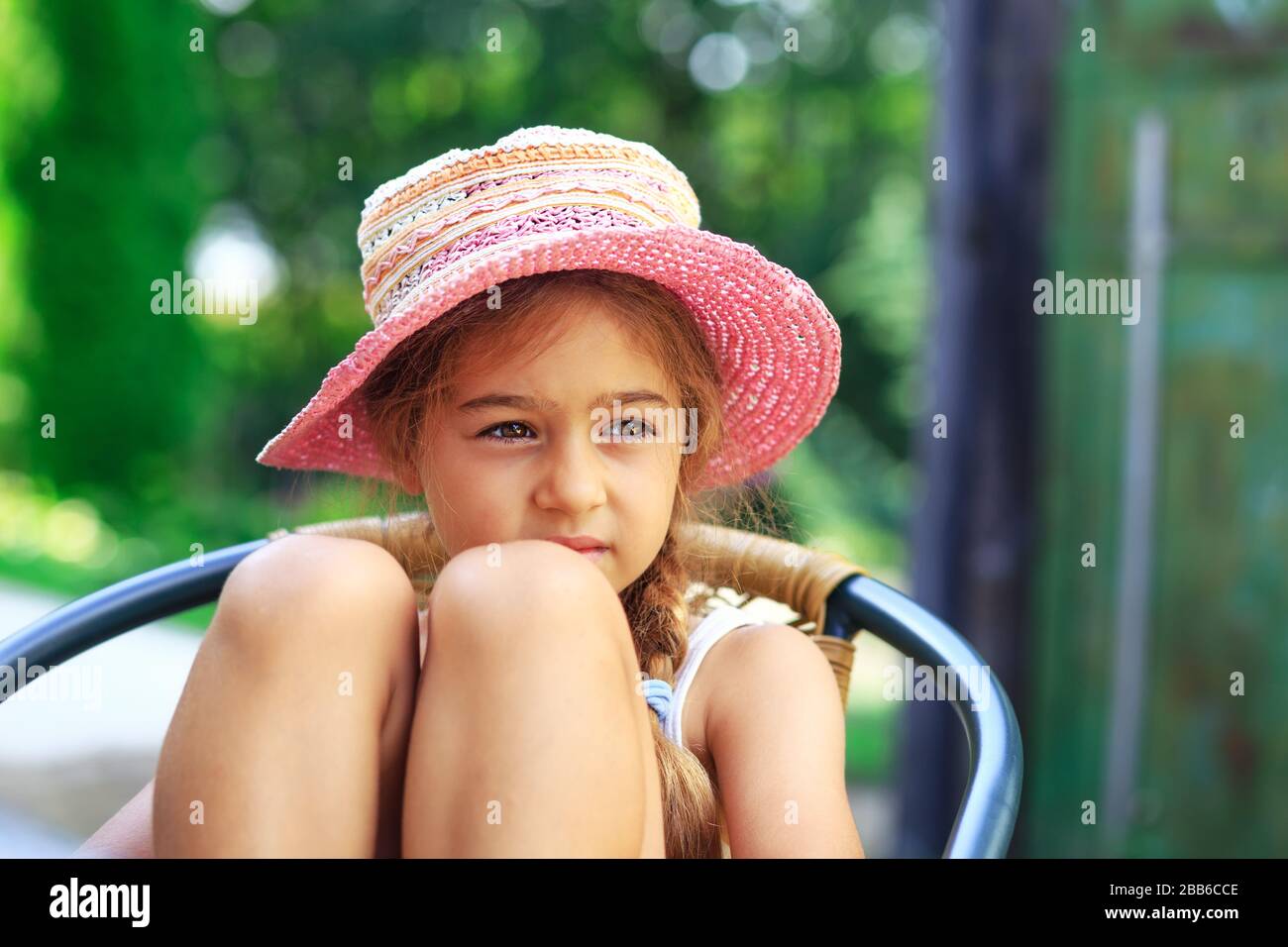 Portrait des süßen traurigen kleinen Mädchens auf dem großen Hut, das am Sommertag traurig aussieht Stockfoto