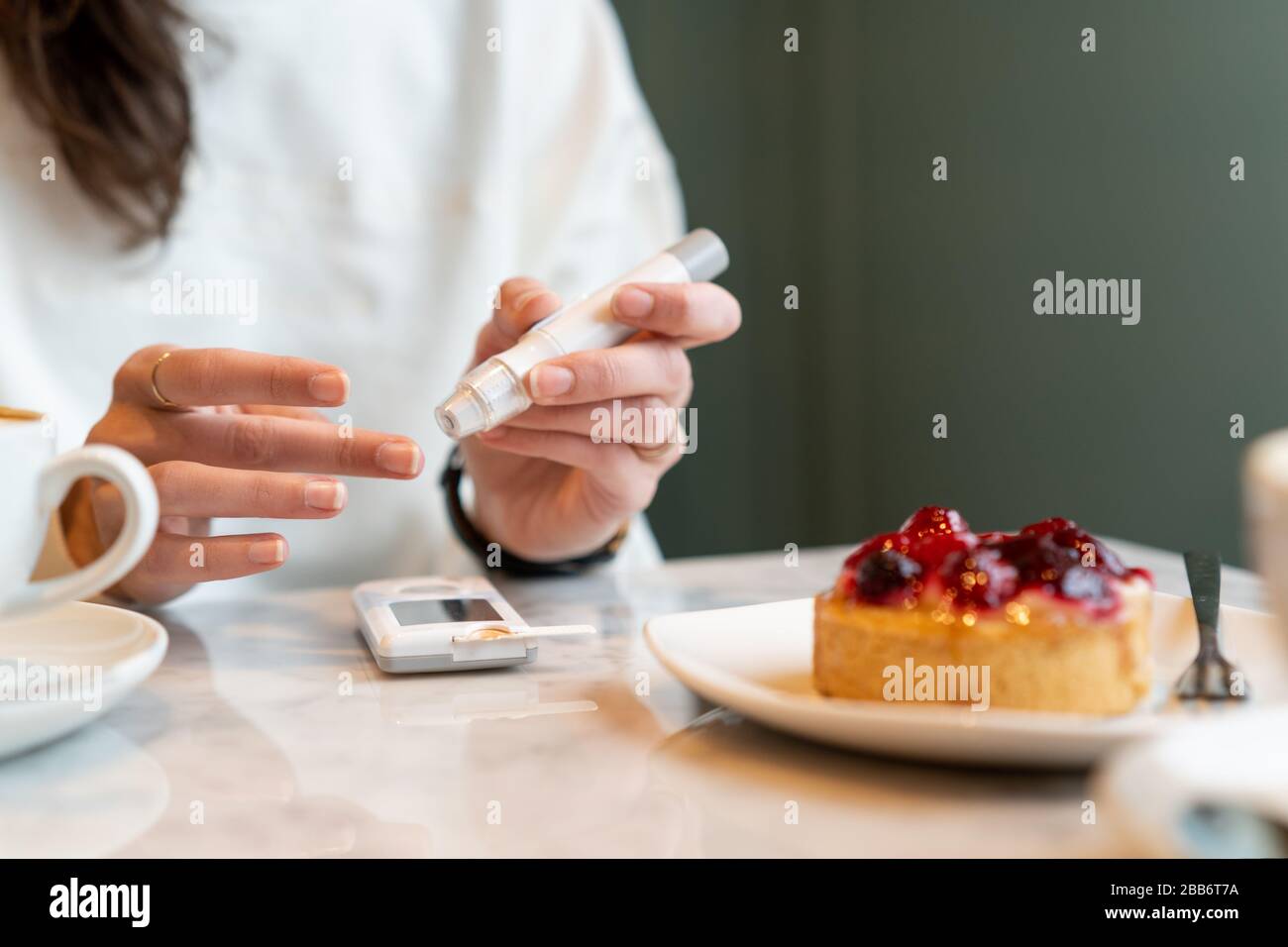 Frau, die ihre Insulinwerte überprüft, bevor sie einen Kuchen isst Stockfoto