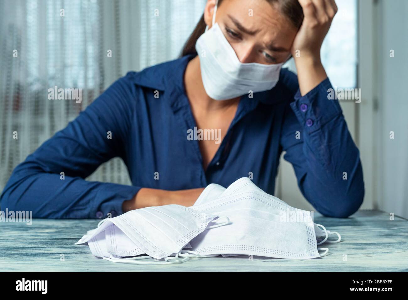 Frau sitzt am Schreibtisch und betrachtet Masken Stockfoto