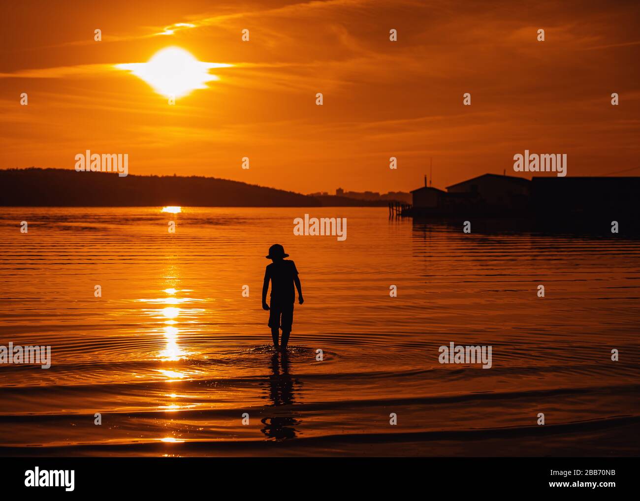 Silhouette eines Jungen, der bei Sonnenuntergang im Meer spazieren ging, Bedford, Halifax, Nova Scotia, Kanada Stockfoto
