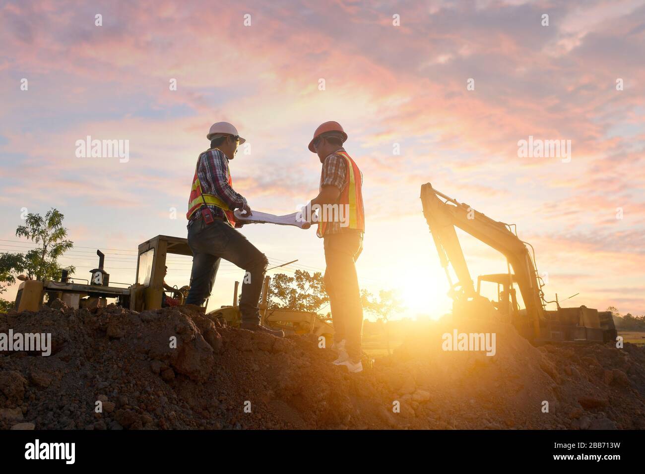 Zwei Bauarbeiter auf einer Baustelle, die sich die Pläne betrachtet, Thailand Stockfoto