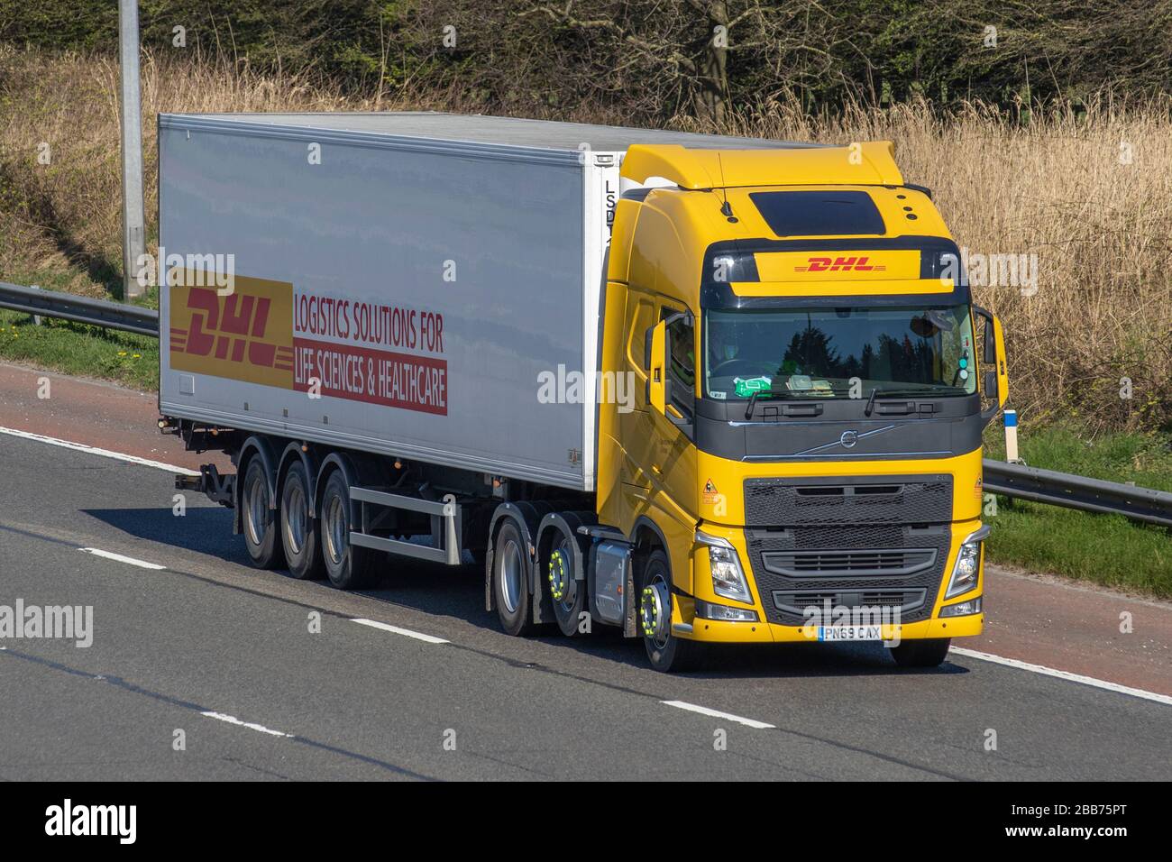 DHL International Shipping; Gelber Transport Lieferwagen, LKW, Transport, Volvo FH Truck, Cargo Carrier, Vehicle, Commercial Transport, Industry, M6 in Manchester, Großbritannien Stockfoto
