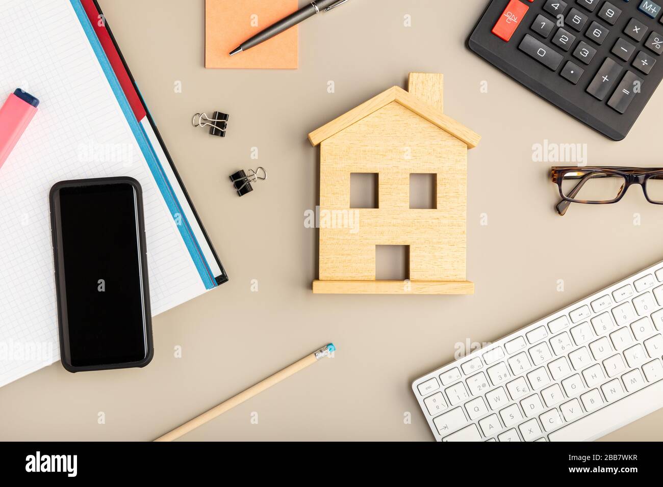 Arbeiten Sie zu Hause. Schreibtisch mit Haus-Symbol, Smartphone, Tastatur und Bürozubehör Stockfoto