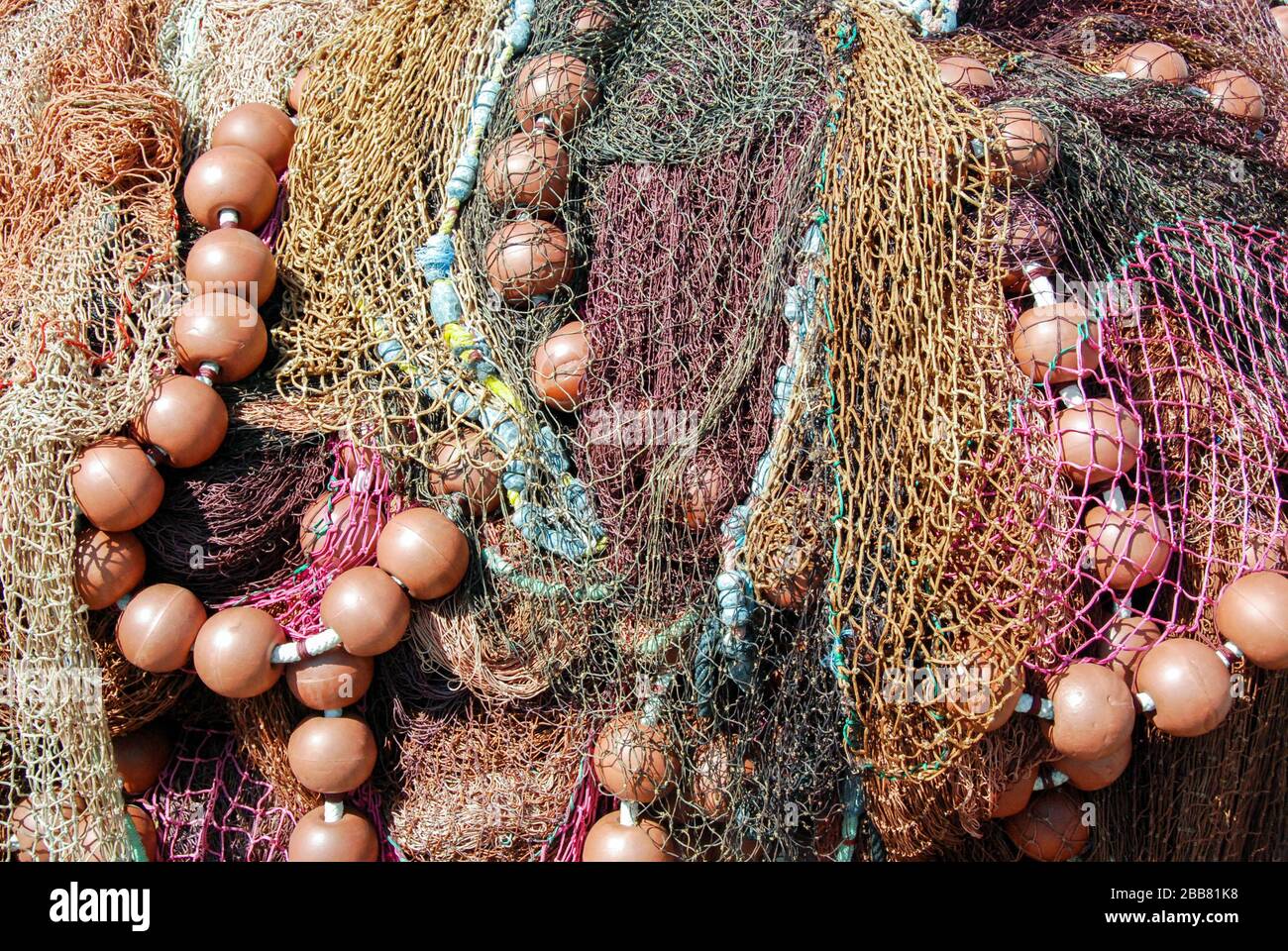 Nahaufnahme der Fischernetze, die mit Schwielen austrocknen, die an der Seite eines Hafengeländes befestigt sind Stockfoto