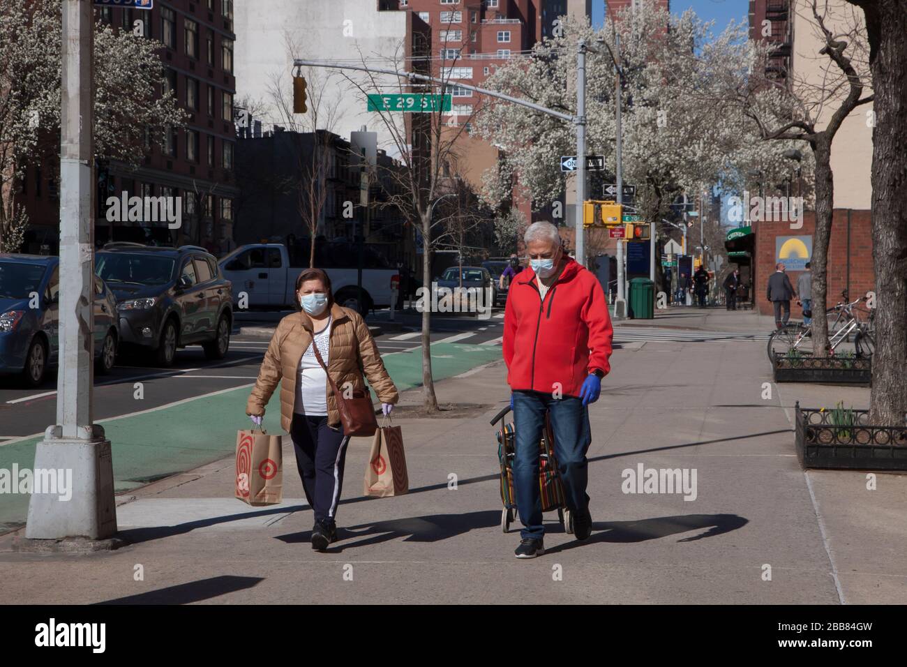 Menschen, die Gesichtsmasken tragen, während sie während der Covid-19-Epidemie (Coronavirus) auf den Bürgersteigen von New York City spazieren. Stockfoto