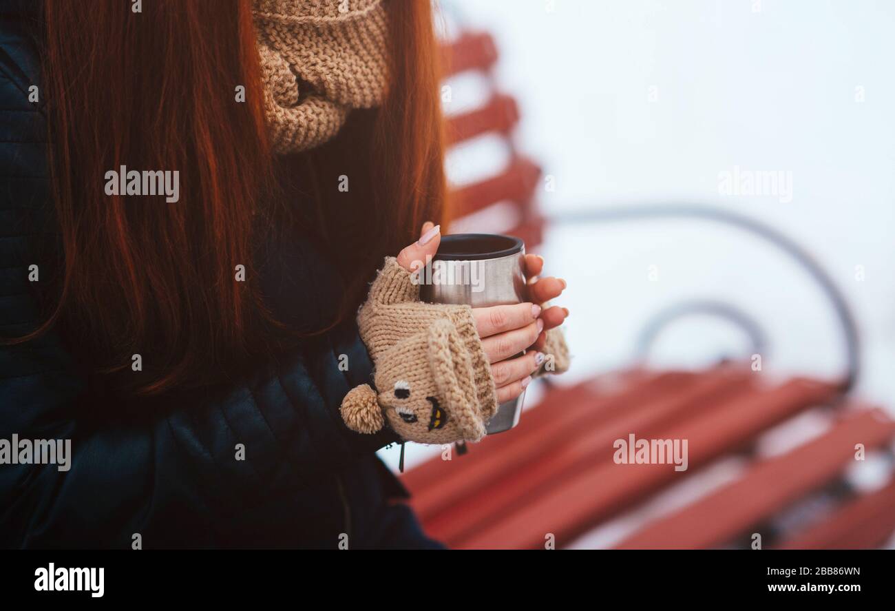 Winter. Frau trinkt heißen Tee oder Kaffee mit eiserner isolierter Tasse. Stockfoto