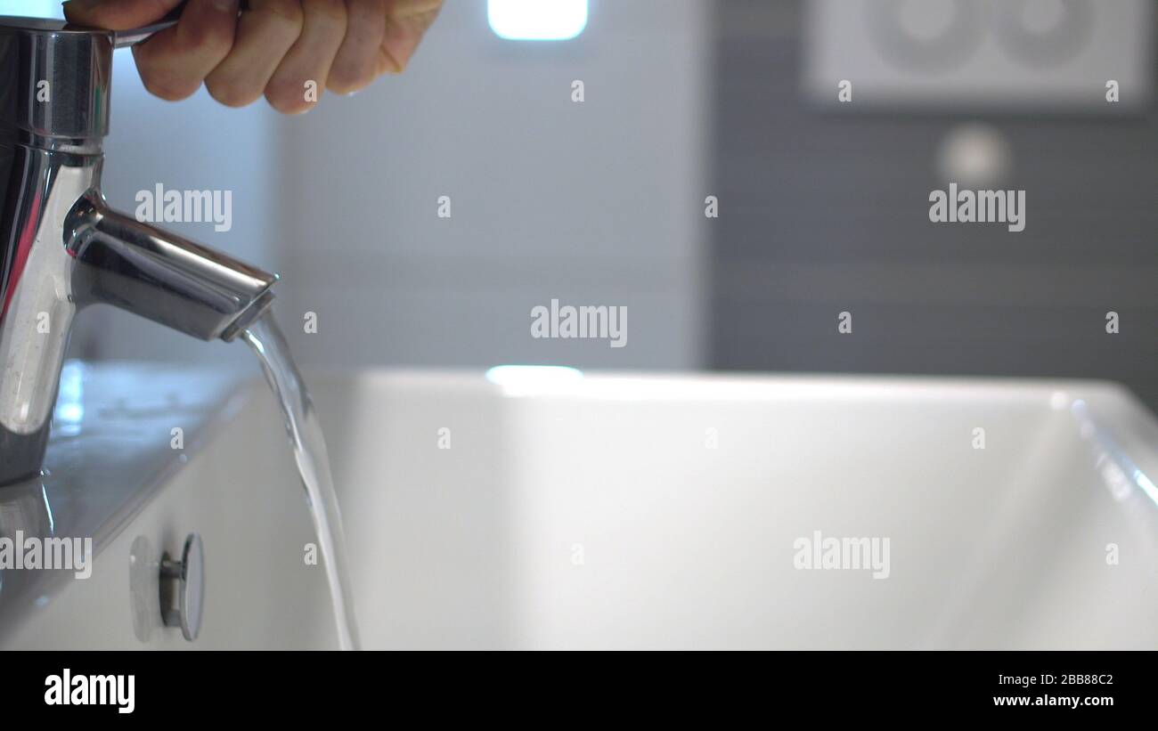 Infektionsprävention. Person, die Wasser am Waschbecken öffnet Stockfoto
