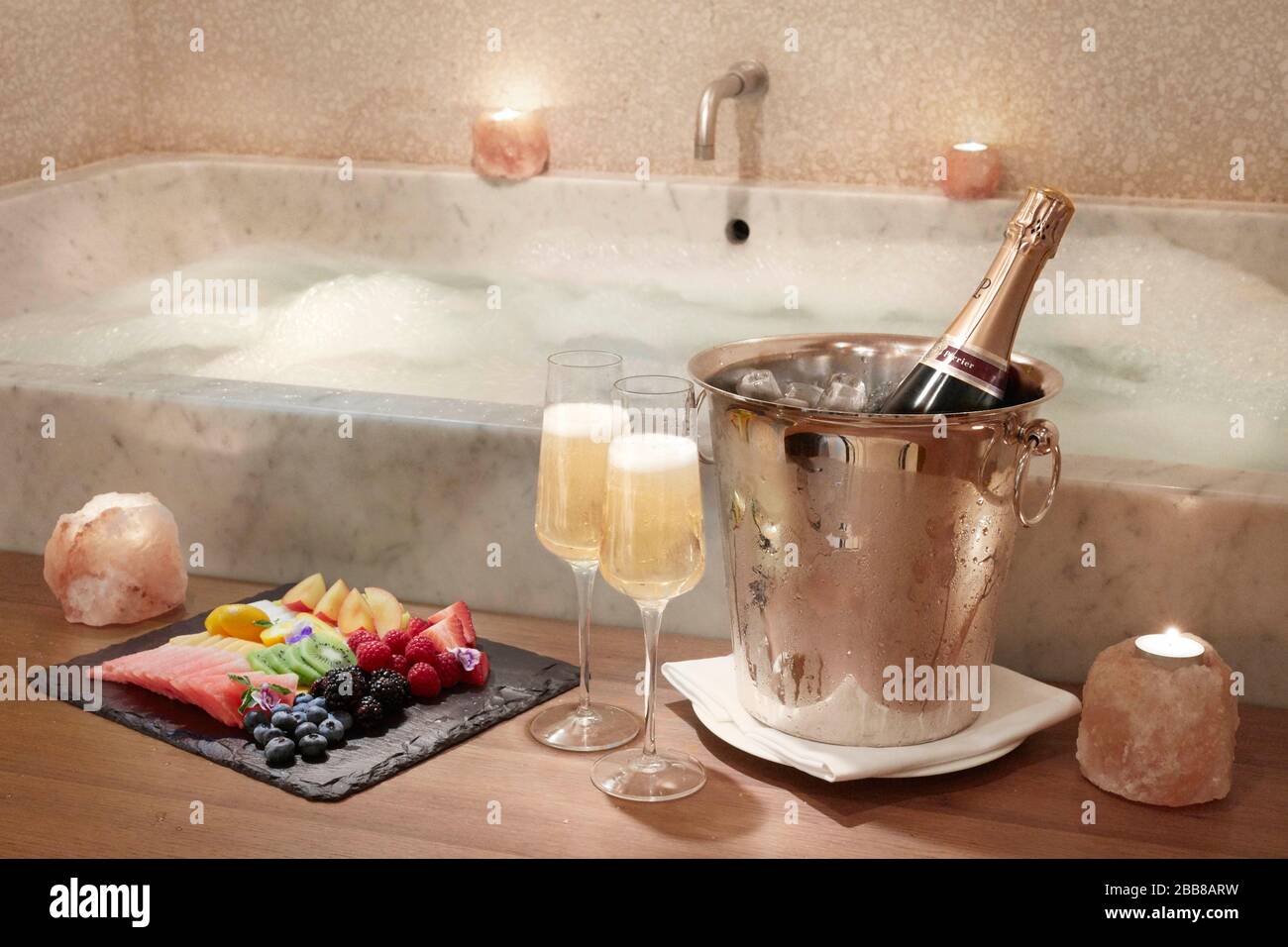 Romantisches Schaumbad Champagnerkerzen Essen Eiskübel Marmorwanne stimmungsvoll sexy Paar Retreat intimes Hotel extravagante Liebe Flitterwochen Stockfoto