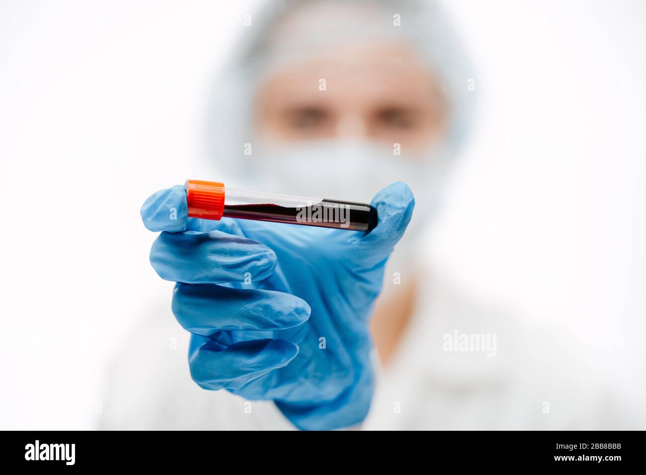 Wissenschaftler in Schutzhandschuhen, die Blutschlauch mit Coronavirus in der Klinik halten Stockfoto