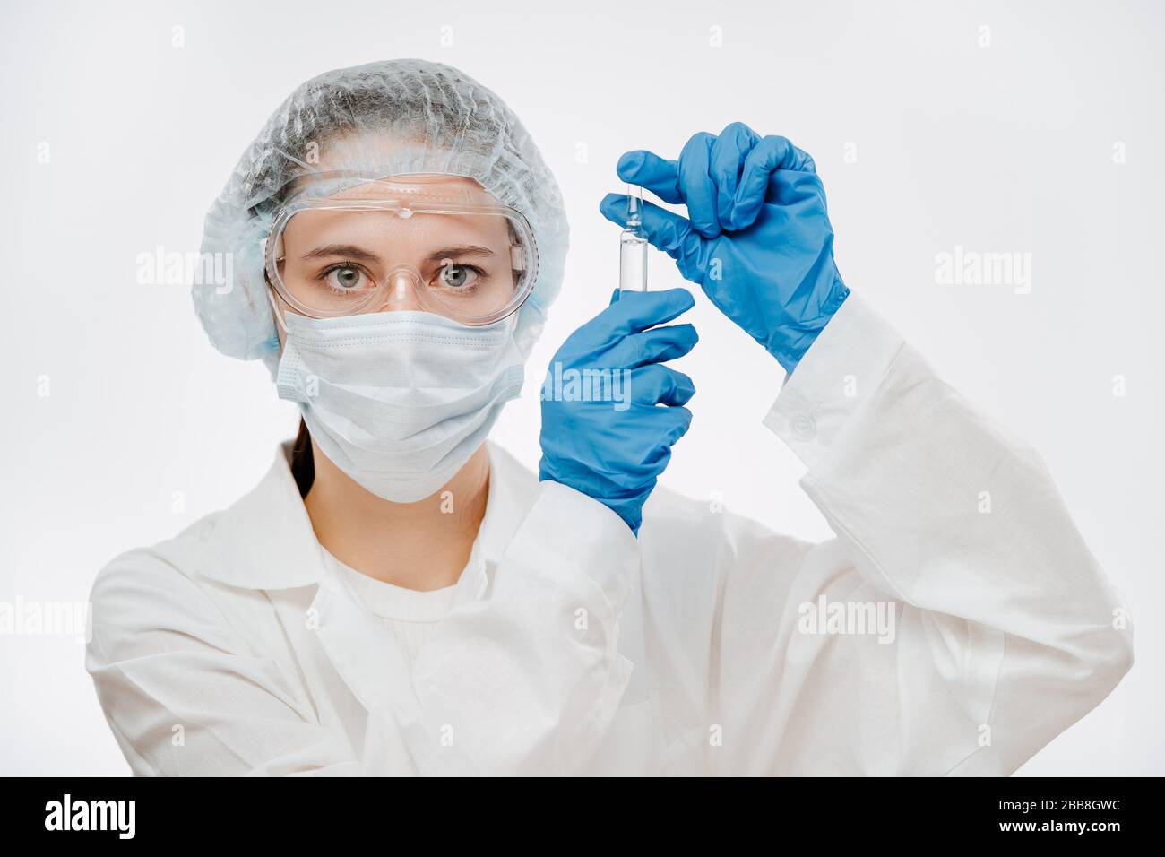 Weibliche Ärztin in Schutzkleidung und Maske, die Medikamente für Coronavirus hält Stockfoto