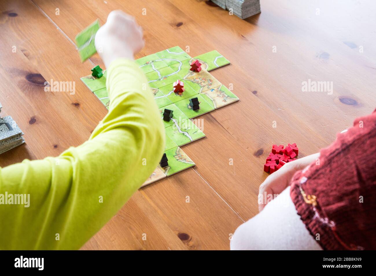 Kind und Mutter spielen Carcassone Brettspiel zu Hause, Quarantäneaktivität Stockfoto