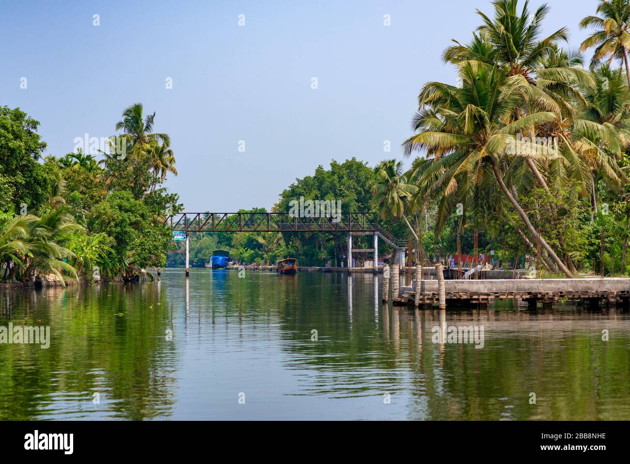 Alleppey, Kerala, Indien - 30. März 2018: Backwaters Kanal mit Palmen und Eisenbrücke. Am Morgen mit einem kleinen roten Boot in die gefahren Stockfoto