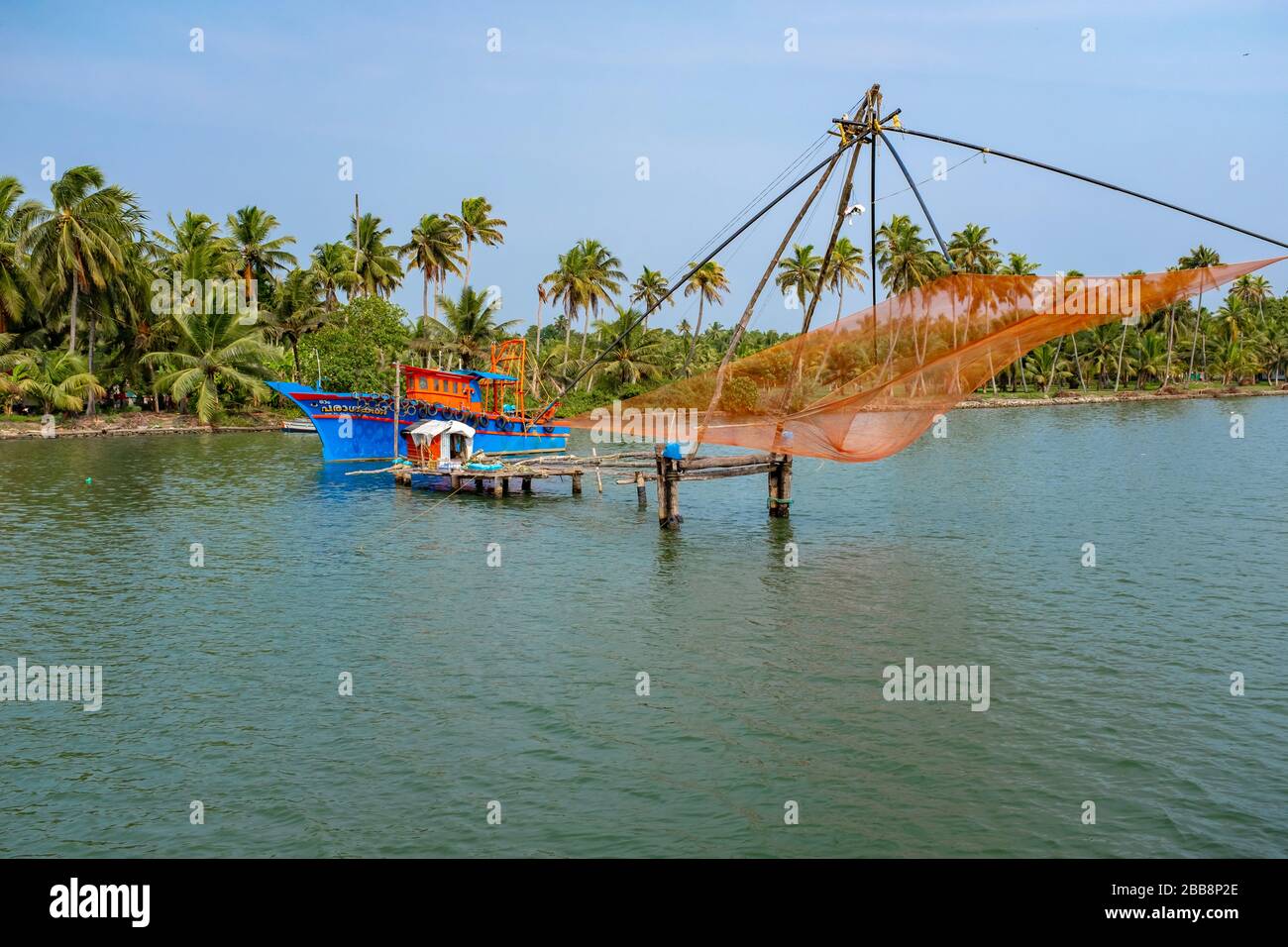 Kerala, Indien - 31. März 2018: Fischerboot und traditionelles Fischernetz auf den Rückwässern. An einem sonnigen Frühlingnachmittag ohne Menschen. Stockfoto