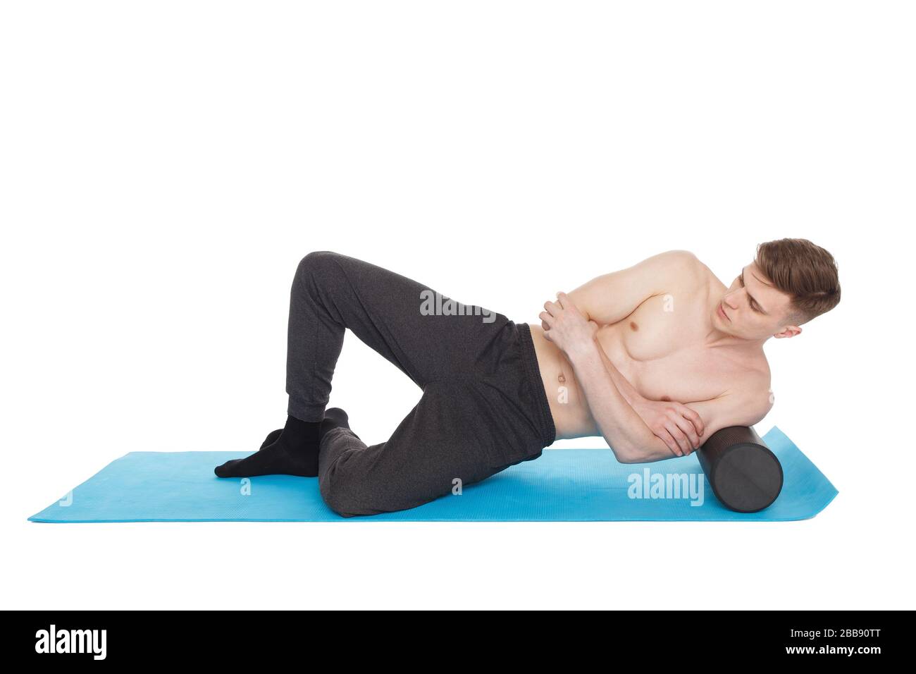 Der gutaussehende Mann zeigt Übungen mit einer Schaumstoffrolle für eine Myofaszialmassage auf der Trainingsmatte im Studio. Isoliert auf weiß. Stockfoto