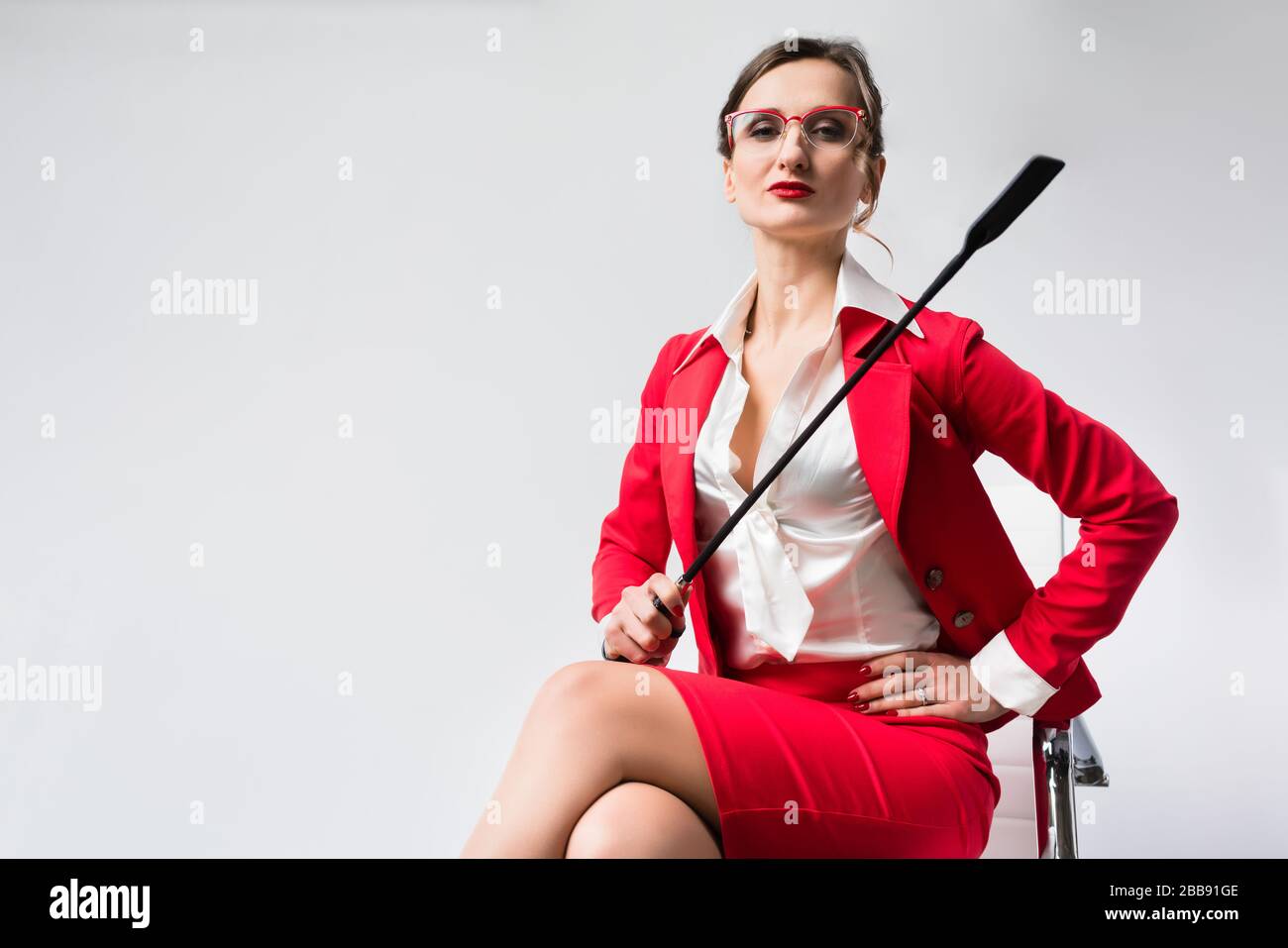 Arrogante Geschäftsfrau mit Peitsche in ihrem Stuhl Stockfoto