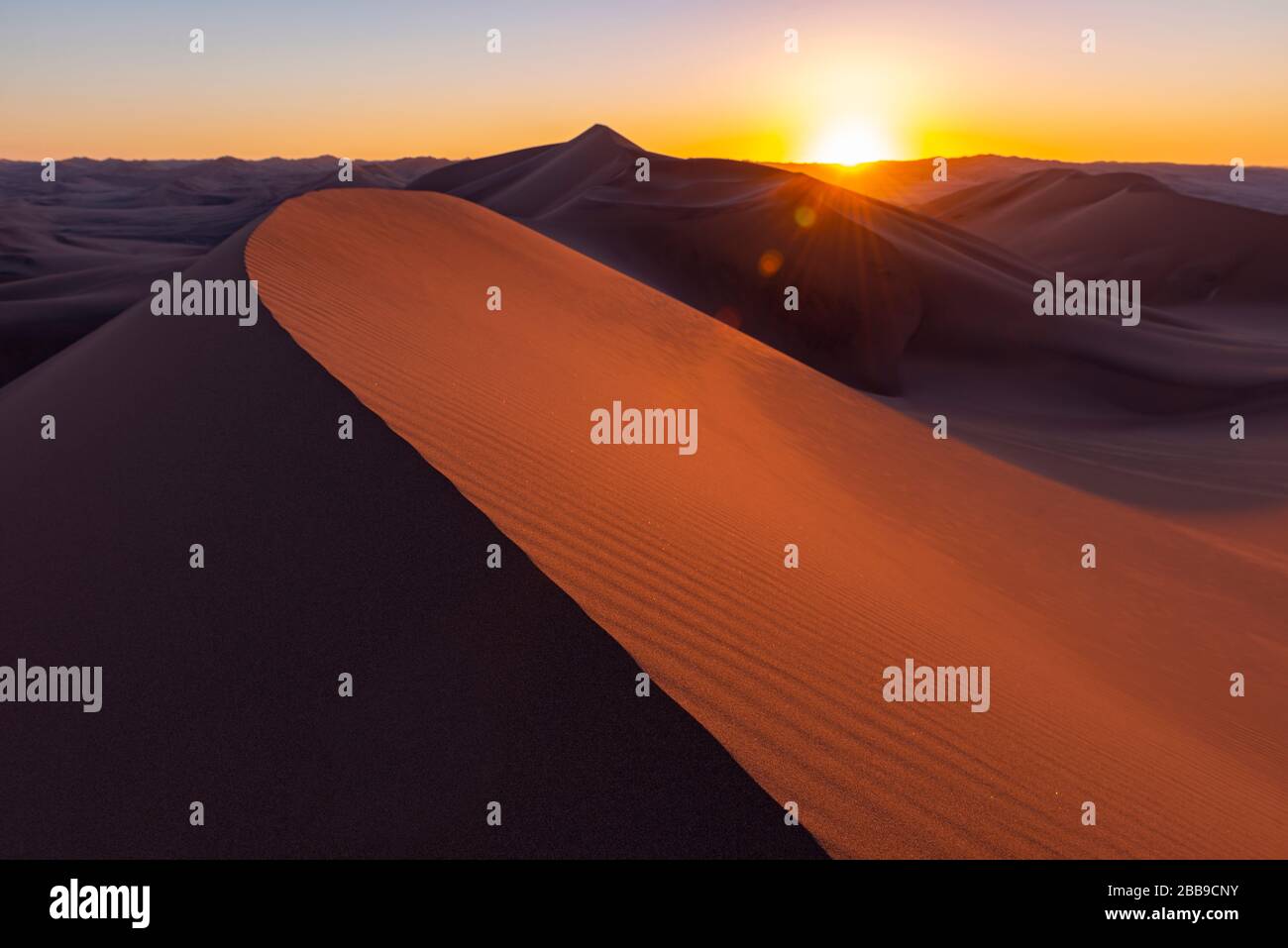 Schatten und Licht bei Sonnenuntergang in den riesigen Sanddünen der Wüste zwischen Ica und Huacachina, Peru. Scharf im Vordergrund, unscharf im Hintergrund, Linsenfland. Stockfoto