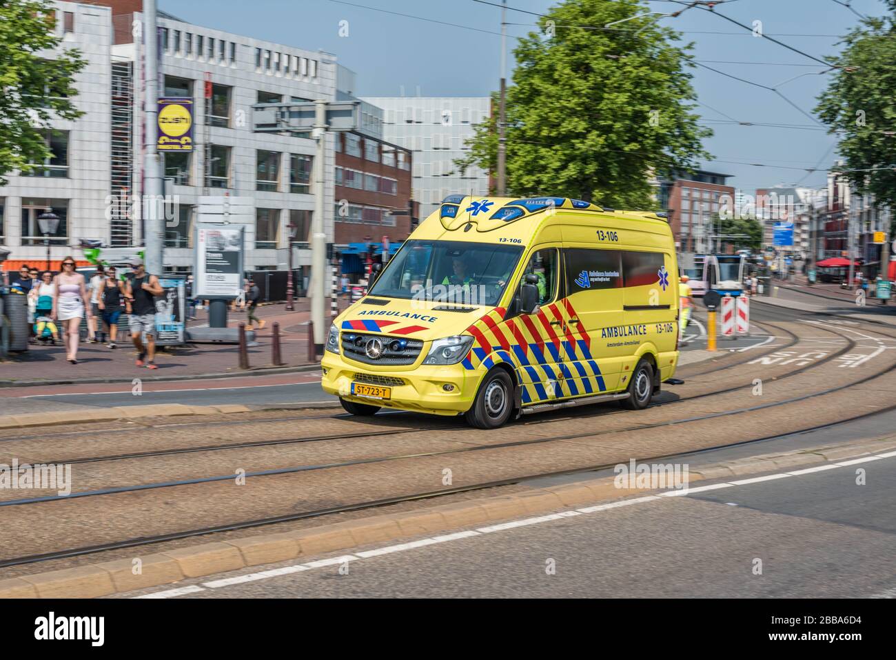 Amsterdam, Holland, Niederlande, August 2018, Rettungswagen, der durch das Zentrum von Amsterdam in der Nähe der Stopera über die Brücke am Fluss Amstel Yell beschleunigt Stockfoto