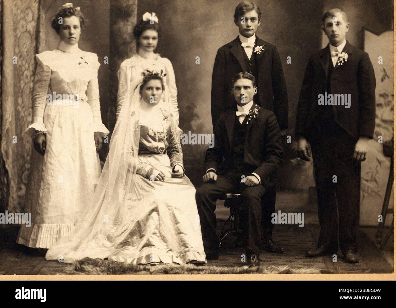 1900 ca. , Oshkosh , Winsconsin , USA: Ein Ehepaar posiert im Atelier des Fotografen SPOSI - SPOSALIZIO - MATRIMONIO - JUST MARRIED - MARRIAGE - Coppia - marito e Moglie - Ehemann und Ehefrau - abito da sposa - Hochzeitskleid - Schleier - velo - Krawatte - papillon - Krawatte - Krawatte - Krawatte - Krawatte - Krawatte - Krawatte - Krawatte - Colletto - papillon - Strascico - poso - Cerimonia di nozze - gente comune - normale Leute - FOTO STORICHE - GESCHICHTE - Album - vita privata - Privatleben - MODE - MODA - Kostüm - testimonio - testimoni - testimone - weiß - bianco --- Archivio GBB Stockfoto