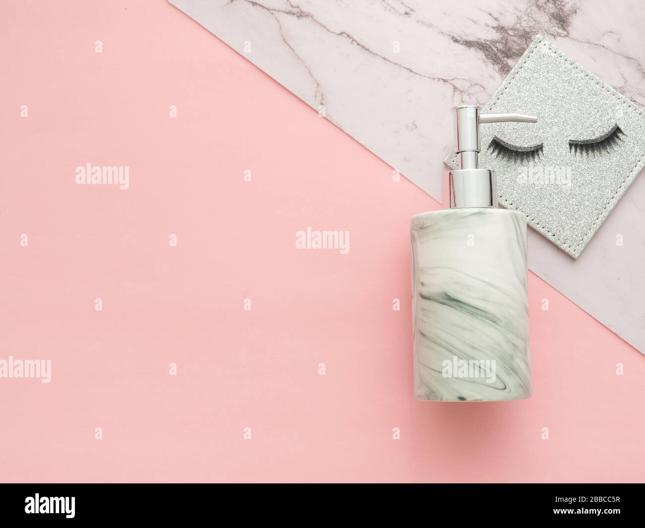 Shampoo oder Gel Pumper Flasche und falsche Wimpern isolierten zwei farbige Marmorfarben und pinkfarbenen Hintergrund. Flaches Lay, horizontales Bild in der Draufsicht Stockfoto