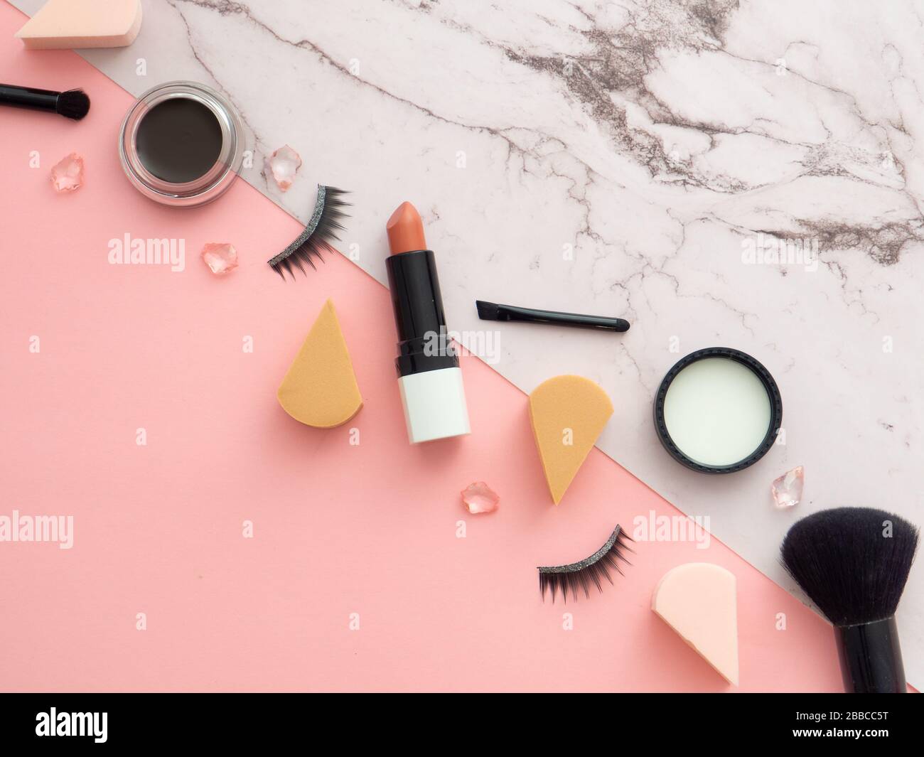 Weibliche Mode Beauty Blogger Arbeitsbereich. Makeup Tools, Kosmetikprodukte, isoliert auf zweifarbigem Marmor- und pinkfarbenem Hintergrund mit Kopierraum f Stockfoto