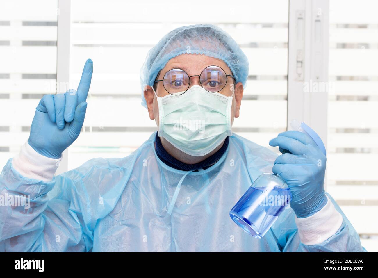 Arzt im Schutzanzug, der antibakterielles Aerosol aus der Flasche sprüht. Medizinisches Personal zeigt ein Desinfektionsmittel. Stockfoto