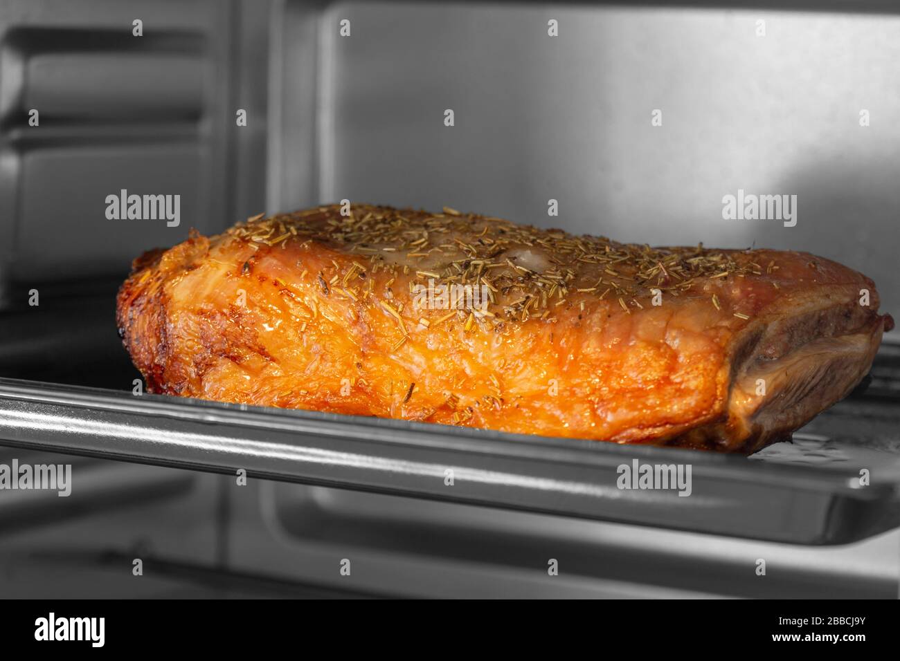 Lammkeule auf einem Backblech, das in einem elektrischen Ofengrill braten soll. Mit selektiver Farbe Stockfoto