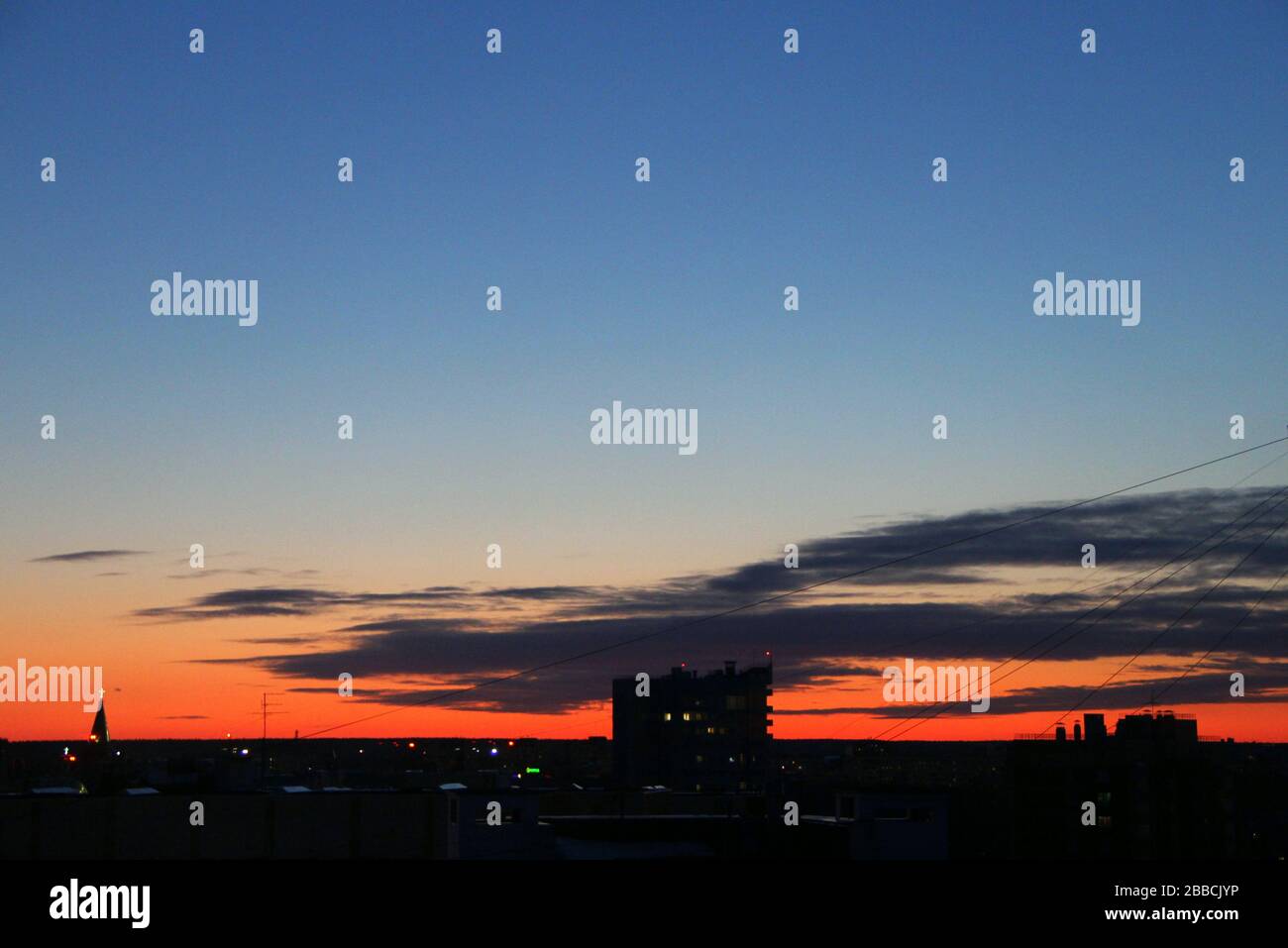 Dramatischer dunkelblauer Himmel mit Wolken bei Sonnenuntergang oder Sonnenaufgang mit einem leuchtend roten Streifen über dem Horizont in der Dämmerung. Stockfoto