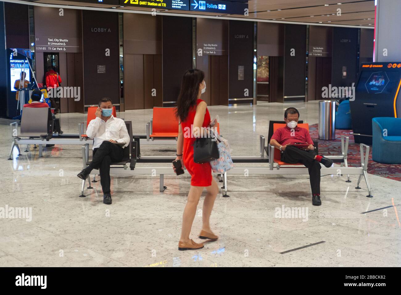 28.03.2020, Singapur, Republik Singapur, Asien - in der Ankunftshalle der T1 des Flughafens Changi decken die Menschen ihre Gesichter mit Gesichtsschutzmasken ab. Stockfoto