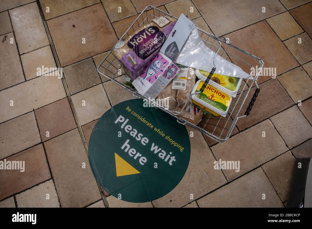 Soziale Distanzierung auf dem Fußbodenschild, das angibt, wo Käufer stehen, während sie in der Schlange am Zahlungsterminal eines Supermarkt-Checkout-Bereichs in London, Großbritannien stehen Stockfoto